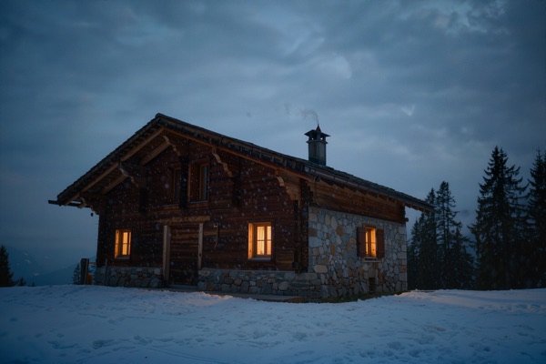 Mountain chalet glowing at blue hour in snowfall